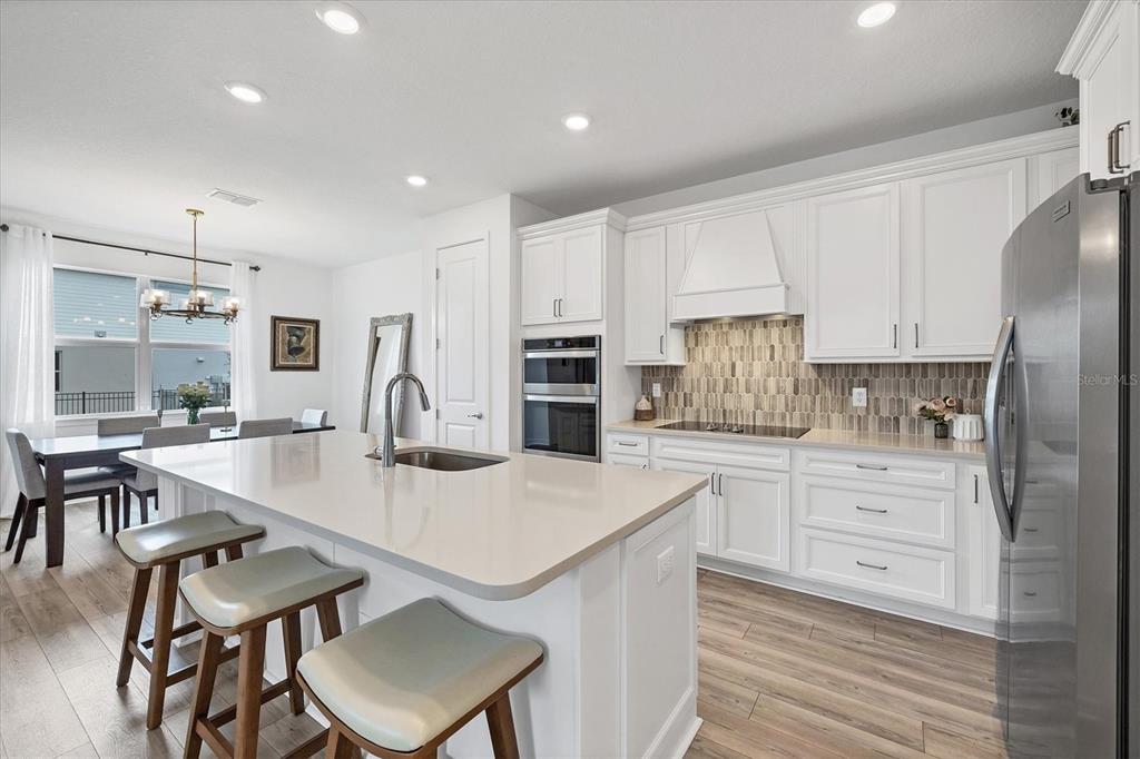 9528 Lamine Way Parrish, FL 34219 - Photo 18 of 58 a kitchen with stainless steel appliances kitchen island granite countertop a table chairs refrigerator and cabinets