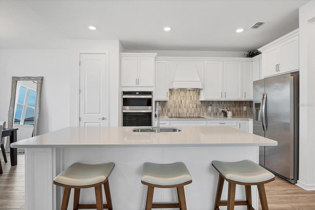 9528 Lamine Way Parrish, FL 34219 - Photo 24 of 58 a kitchen with stainless steel appliances a table chairs refrigerator and sink