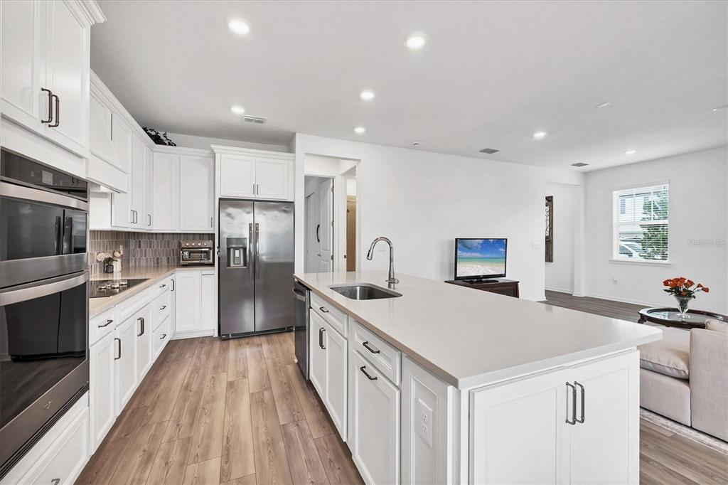 9528 Lamine Way Parrish, FL 34219 - Photo 25 of 58 a kitchen with stainless steel appliances a sink a stove a refrigerator cabinets and a center island