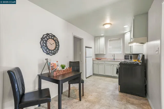 a kitchen with a refrigerator a stove top oven a dining table and chairs