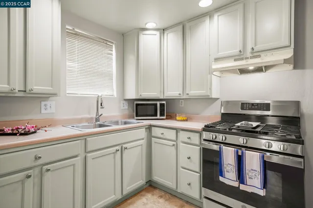 a kitchen with stainless steel appliances granite countertop a sink a stove and cabinets