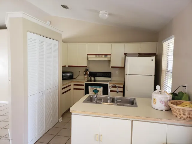 a kitchen with a refrigerator and white cabinets