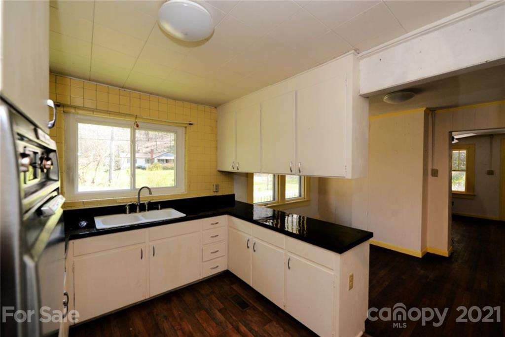 1 Sycamore Street Asheville, NC 28804 - Photo 18 of 46 a kitchen with a sink dishwasher a stove and white cabinets with wooden floor
