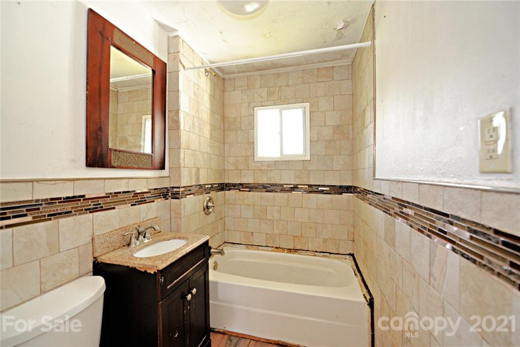 1 Sycamore Street Asheville, NC 28804 - Photo 19 of 46 a bathroom with a granite countertop sink mirror vanity and a bathtub