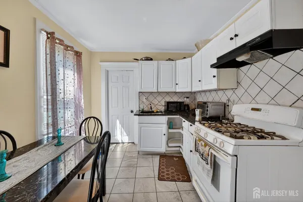 a kitchen with stainless steel appliances granite countertop a stove a sink dishwasher and white cabinets with wooden floor