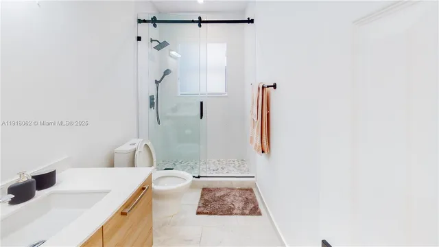 a bathroom with a granite countertop sink a toilet and shower