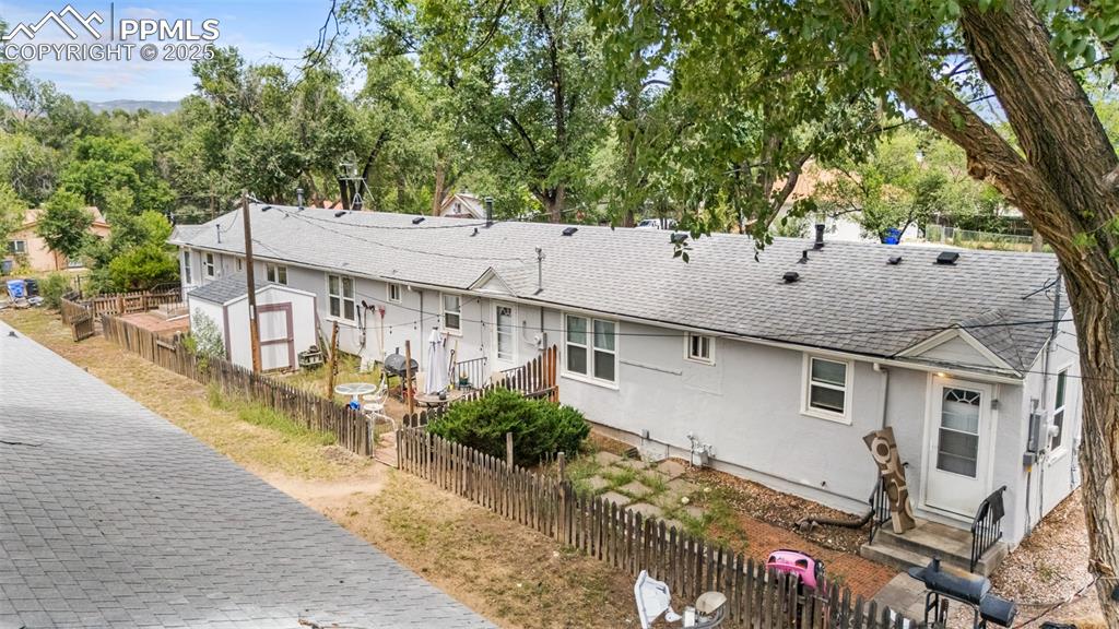 317 West Harrison Street Colorado Springs, CO 80907 - Photo 14 of 22 View of property exterior featuring stucco siding, roof with shingles, and a storage shed