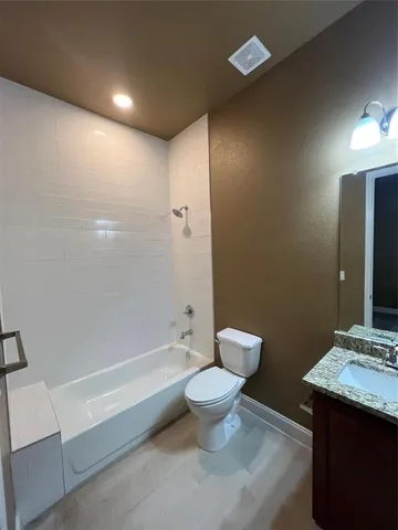 a bathroom with a granite countertop sink a toilet and shower