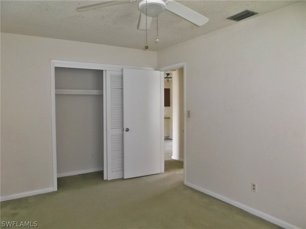 108 Rowland Road Lehigh Acres, FL 33936 - Photo 6 of 8 an empty room with a ceiling fan and closet area