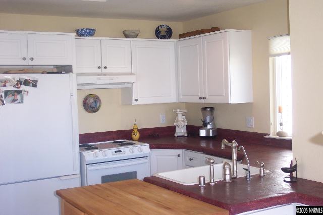 7187 Blue Falls Circle Reno, NV 89511 - Photo 2 of 5 a kitchen with kitchen island a sink a stove and white cabinets
