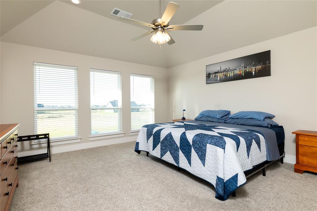 321 Monument Pl. Azle, TX 76020 - Photo 19 of 38 a spacious bedroom with a bed and a ceiling fan
