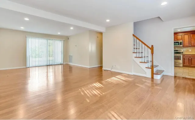 a view of an empty room with wooden floor and stairs