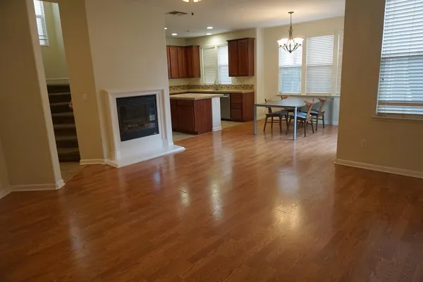 a open kitchen with granite countertop a stove top oven a sink dishwasher a dining table and chairs with wooden floor
