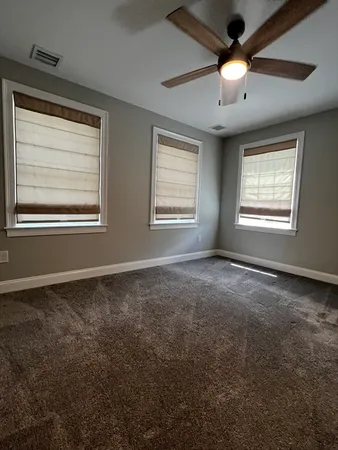 an empty room with chandelier fan and windows