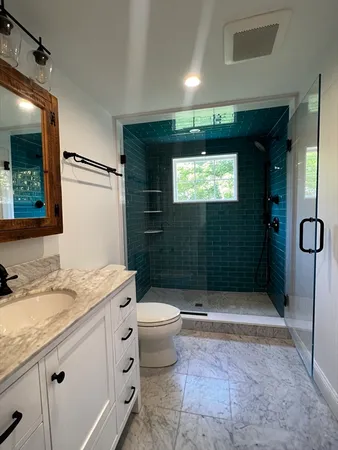 a bathroom with a granite countertop sink a toilet a mirror and shower