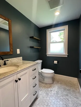 a bathroom with a granite countertop sink toilet and mirror