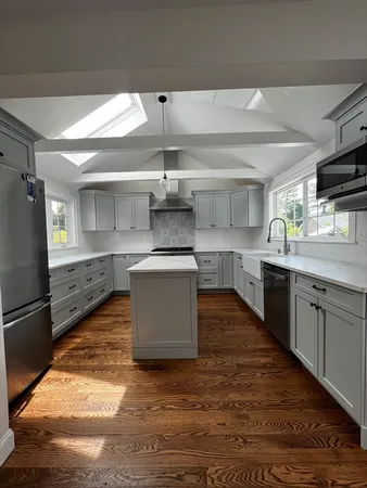 a kitchen with kitchen island granite countertop a sink cabinets and stainless steel appliances