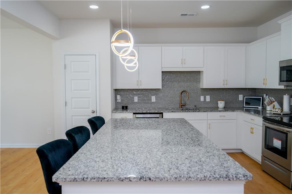 2115 Ravencliff Drive Austell, GA 30168 - Photo 2 of 21 a kitchen with granite countertop a stove a sink and a white cabinets