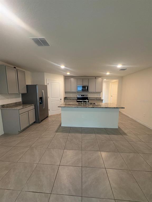 6910 Southeast 112th Street Belleview, FL 34420 - Photo 11 of 20 a large kitchen with stainless steel appliances granite countertop a refrigerator and a stove top oven
