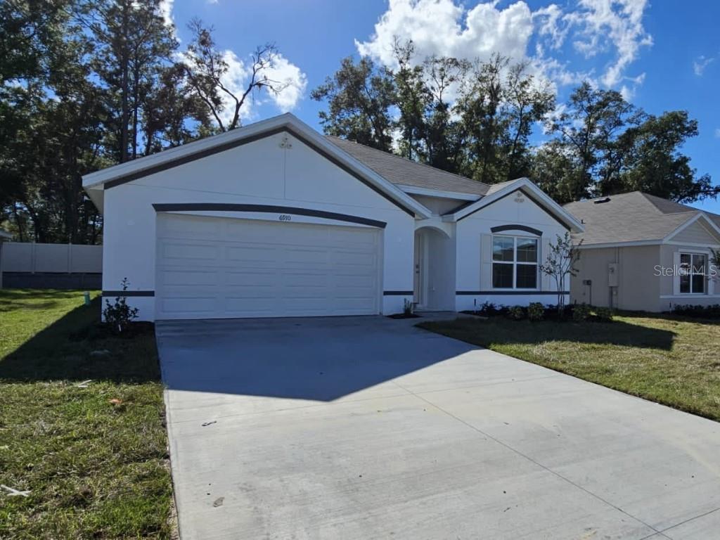 6910 Southeast 112th Street Belleview, FL 34420 - Photo 2 of 20 a front view of a house with a yard and garage