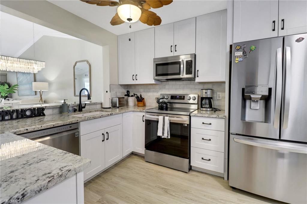 a kitchen with stainless steel appliances white cabinets a sink a stove a refrigerator and microwave