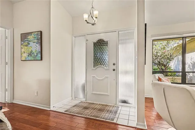 a view of a hallway with windows wooden floor and front door