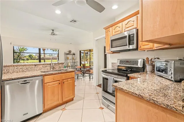 a kitchen with stainless steel appliances granite countertop a stove top oven a sink dishwasher a dining table and chairs with wooden floor