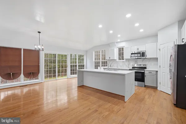 a large kitchen with kitchen island a large counter top space a sink stainless steel appliances and cabinets