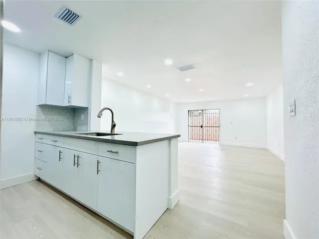 a kitchen with granite countertop a sink and cabinets