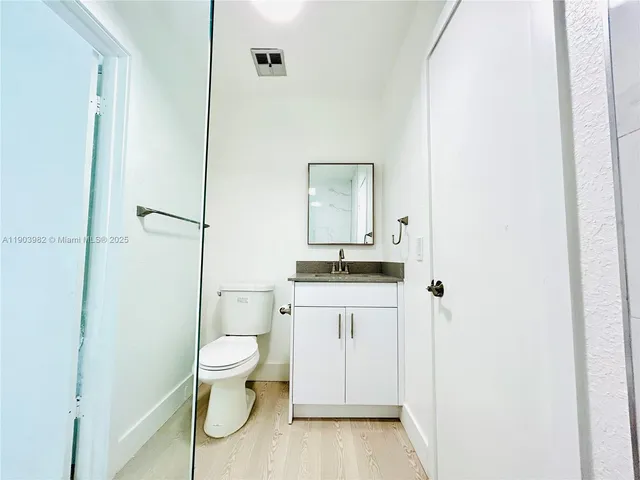 a bathroom with a granite countertop sink toilet and mirror