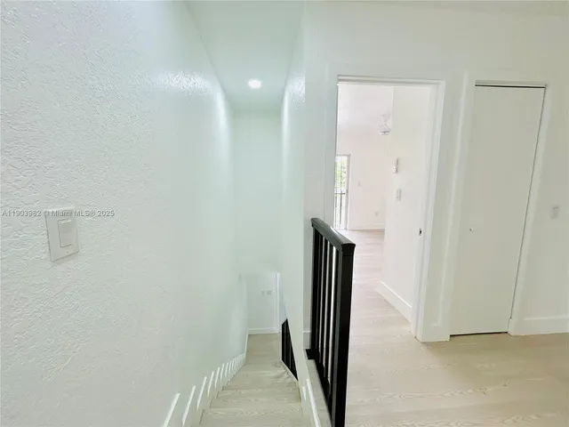 a view of kitchen with refrigerator and white cabinets