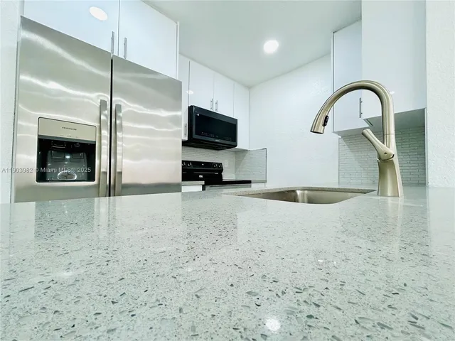a kitchen with kitchen island a sink stainless steel appliances and a counter top space