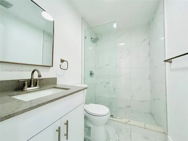 a bathroom with a granite countertop sink a toilet and shower