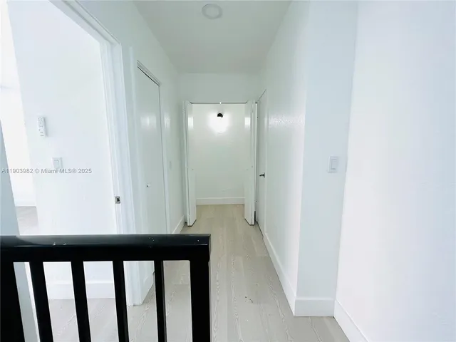 an empty room with wooden floor closet and windows