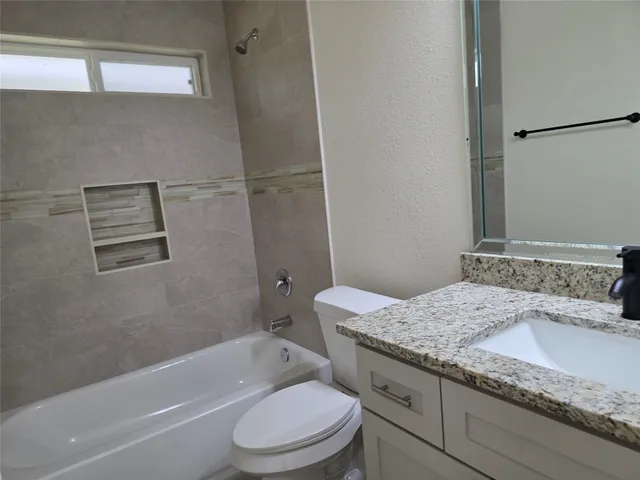 a bathroom with a granite countertop sink a toilet and bathtub