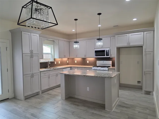 a kitchen with stainless steel appliances granite countertop a sink a stove a refrigerator cabinets and wooden floor