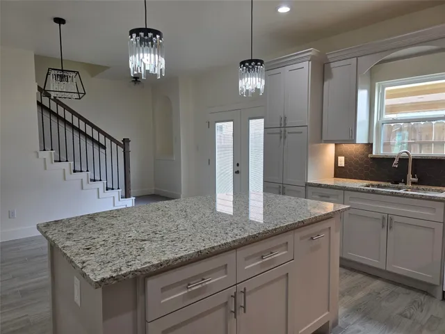 a kitchen with center island white cabinets and chandelier