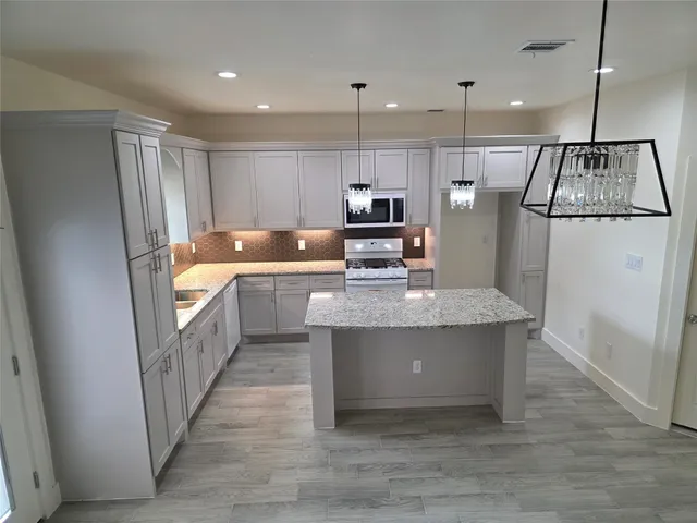 a kitchen with stainless steel appliances granite countertop a refrigerator a sink a stove and a refrigerator