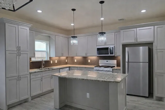 a kitchen with kitchen island a sink stainless steel appliances and cabinets