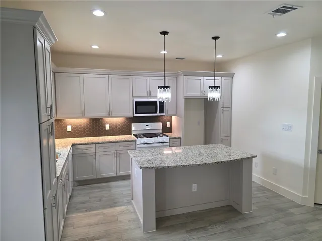 a kitchen with kitchen island granite countertop a sink cabinets and stainless steel appliances