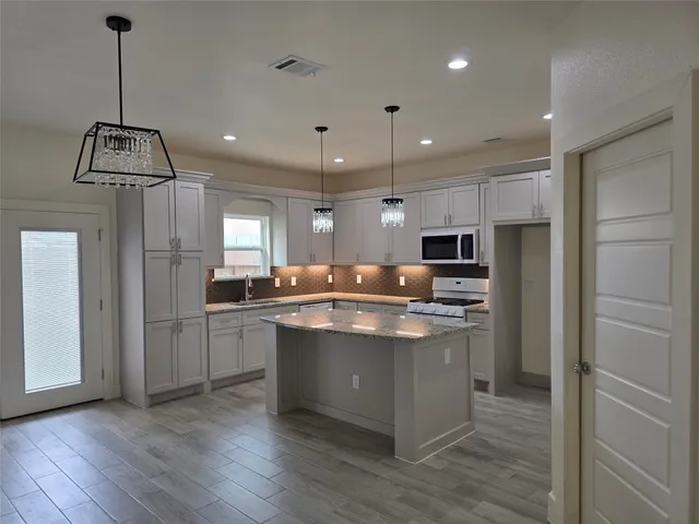 a kitchen with kitchen island stainless steel appliances a sink cabinets and wooden floor
