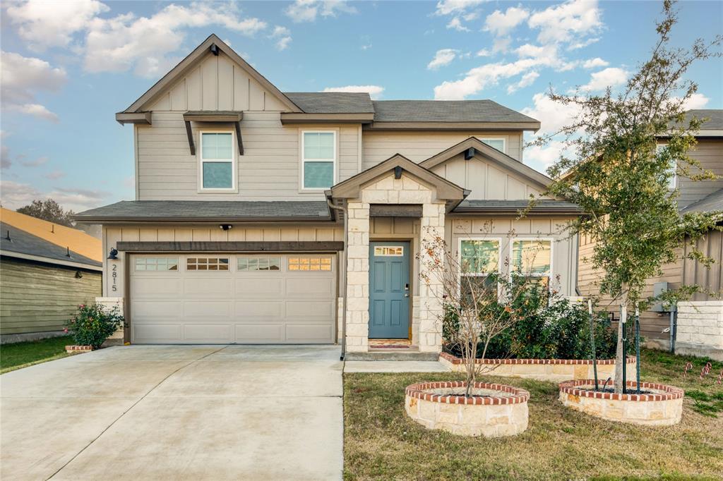 Craftsman-style house featuring board and batten siding, a garage, driveway, and a front lawn