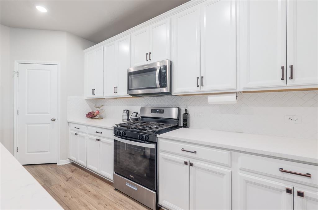 2815 Haystack Lane Round Rock, TX 78665 - Photo 10 of 30 Kitchen with stainless steel appliances, white cabinets, light wood finished floors, backsplash, and recessed lighting