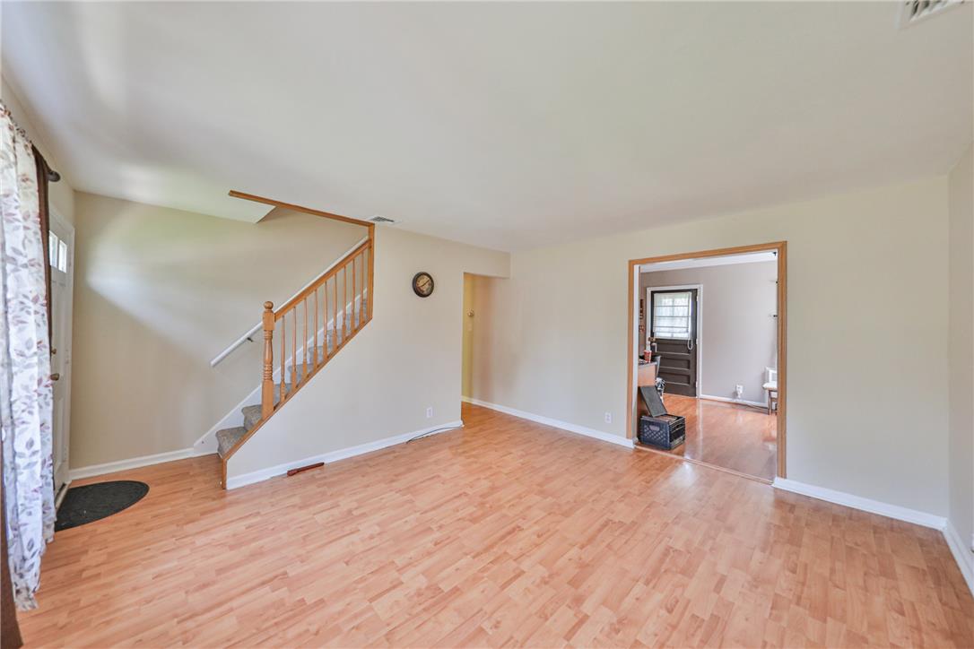 3050 Cornwall Road Bethlehem, PA 18017 - Photo 9 of 80 A well-lit living area features warm wood-tone flooring and a classic wooden staircase leading to the upper level.
