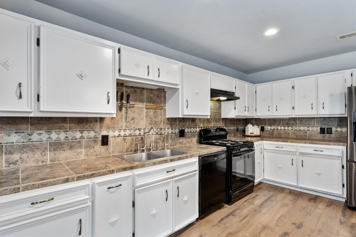 2203 Windy Hill Road Kyle, TX 78640 - Photo 14 of 29 a kitchen with granite countertop white cabinets white stainless steel appliances with a sink and dishwasher
