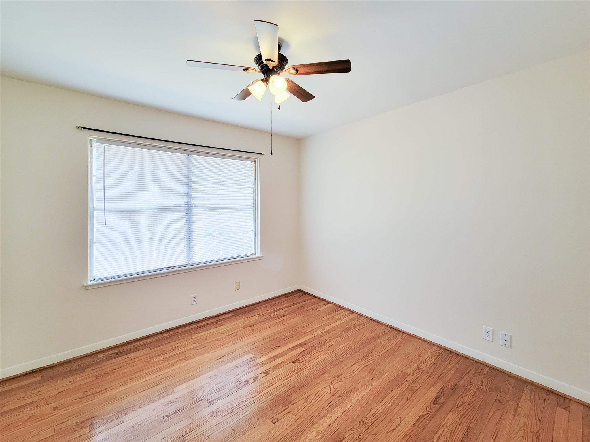5442 Kinglet Street Houston, TX 77096 - Photo 12 of 25 an empty room with wooden floor fan and windows