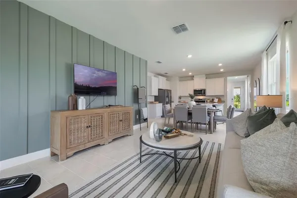 a living room with furniture a flat screen tv and kitchen view