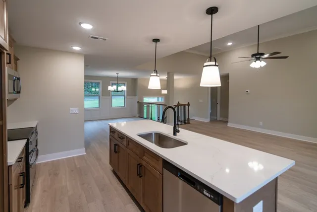 an empty room with windows a fireplace a ceiling fan and wooden floor