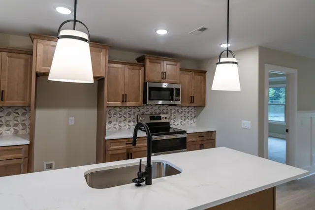 a kitchen with stainless steel appliances a sink a stove top oven a counter space and cabinets