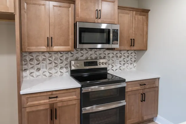 a kitchen with stainless steel appliances granite countertop a sink a refrigerator and a wooden floor